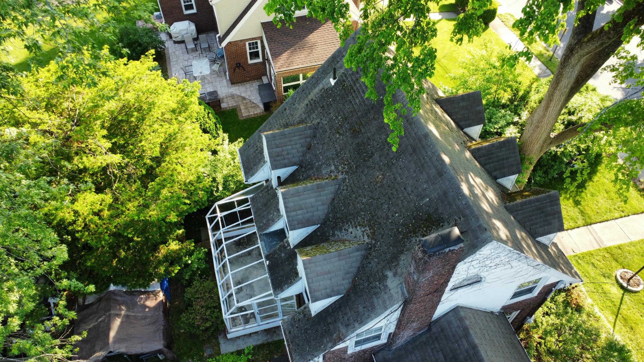 Aerial view of a New Jersey home with an aged shingle roof, multiple dormers and a chimney